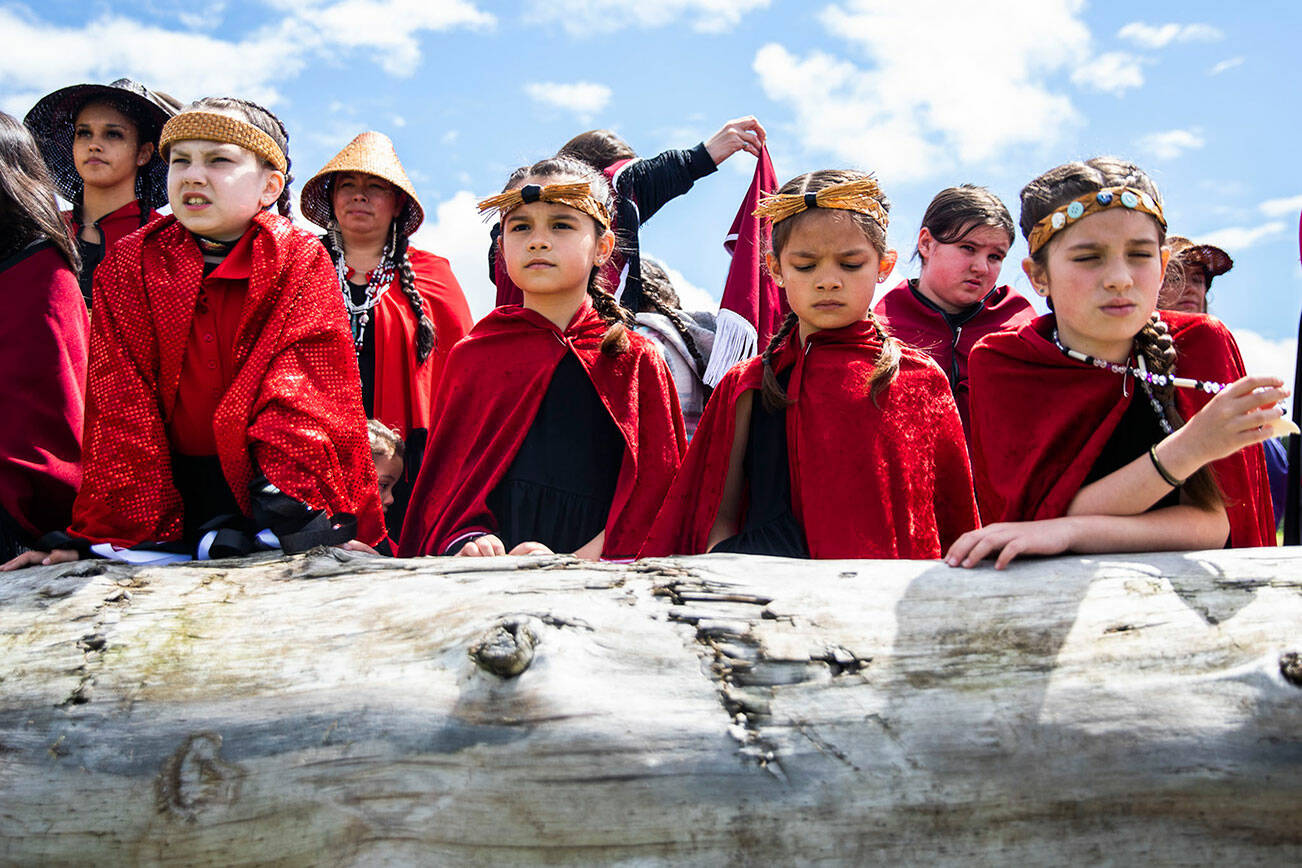 Young girls watch as a canoe carrying an enormous king salmon makes its way to shore on Saturday, June 11, 2022, in Tulalip, Washington. (Olivia Vanni / The Herald)