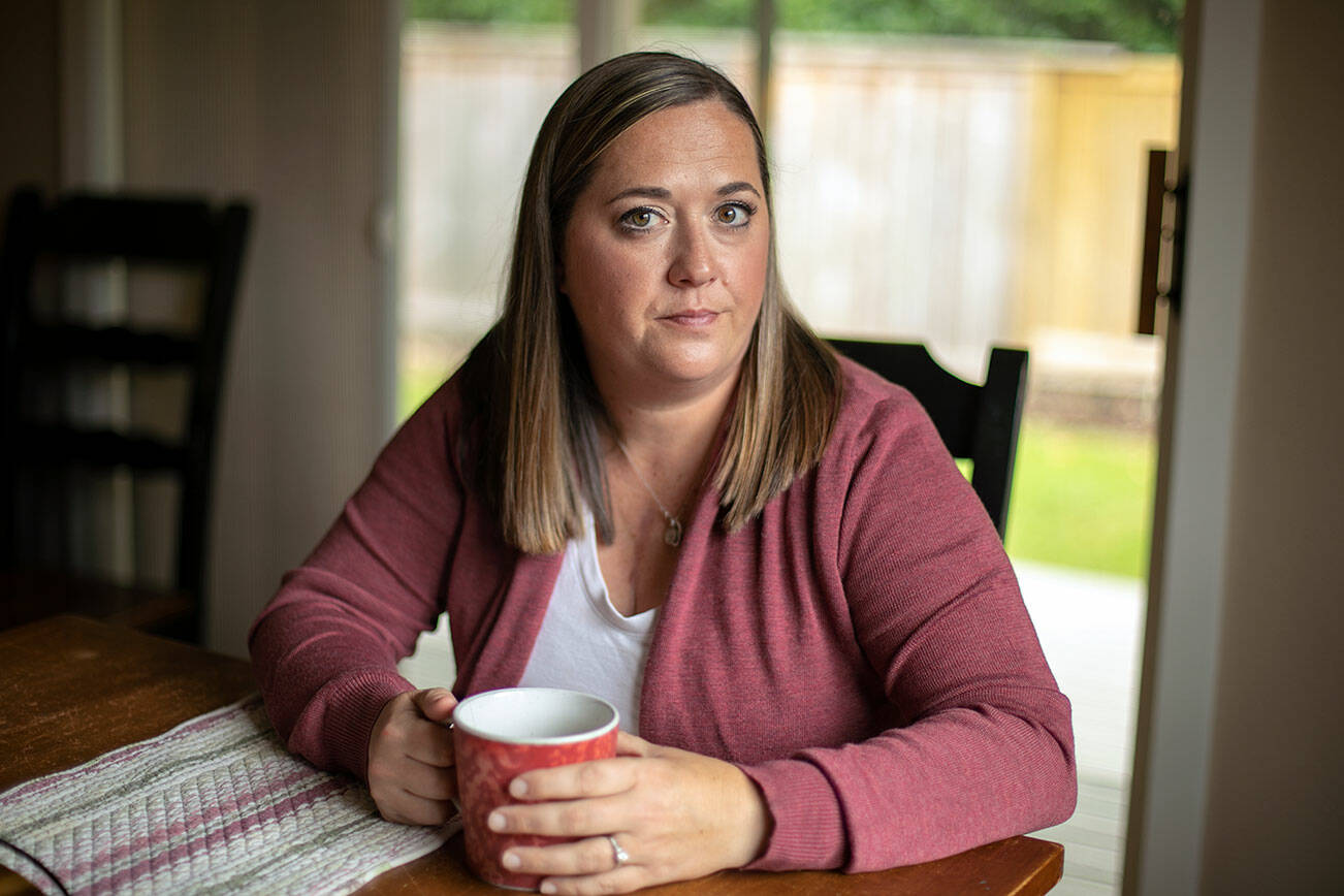 Marie Riley, 42, sits in her dining room with a cup of tea Tuesday, Oct. 25, 2022, at her family’s home in North Bend, Washington. Riley was born with tetralogy of fallot, a rare congenital heart condition that has required multiple open-heart surgeries during her lifetime. (Ryan Berry / The Herald)