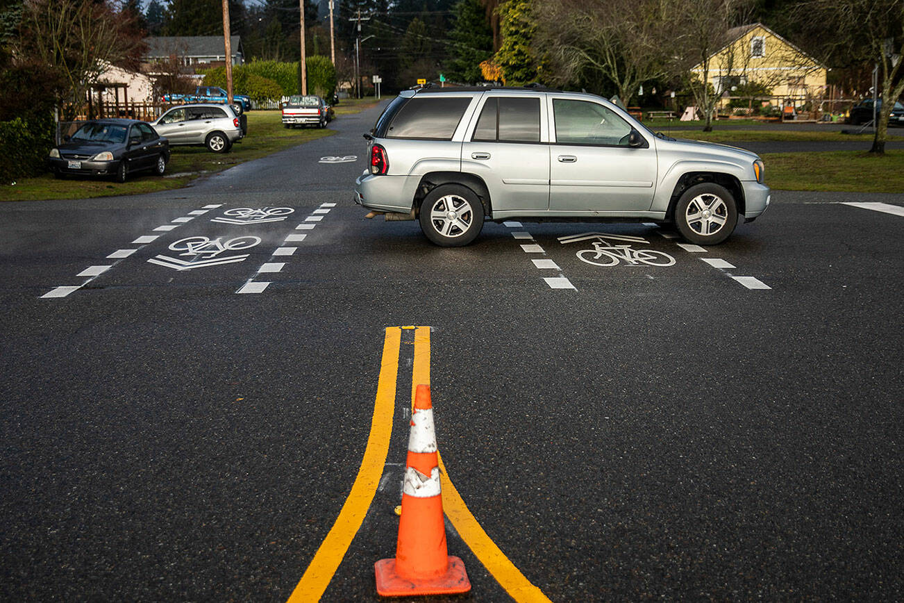 A car drives over newly marked bike lanes at the intersection of College Avenue and 47th Street SE on Friday, Dec. 8, 2023 in Everett, Washington. (Olivia Vanni / The Herald)