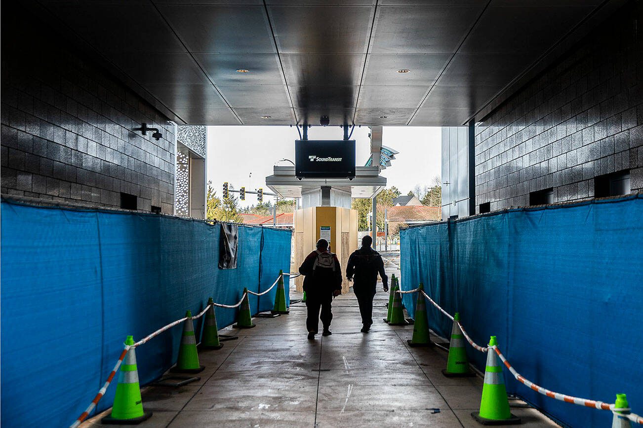 People walk underneath Sound Transit’s Link Lynnwood City Center Station currently under construction on Thursday, Dec. 28, 2023 in Lynnwood, Washington. (Olivia Vanni / The Herald)