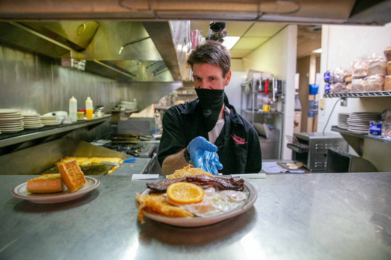 Lead cook Wes Bazin, who has worked at Totem Family Diner on-and-off for more than a decade, puts a #13 up in the window during lunch service at Totem Family Diner on Saturday, Jan. 14, 2023, in Everett, Washington. Totem is one of countless restaurants nationwide feeling the pressure from increased prices and a lower supply of eggs. (Ryan Berry / The Herald)