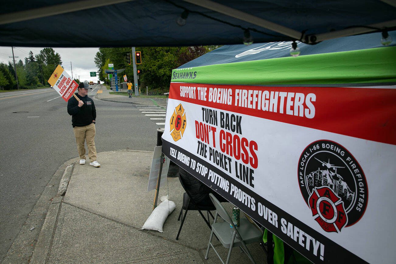 Firefighter Kyle Liston pickets outside of Boeing on Airport Road as the lockout of IAFF Local I-66 Boeing Firefighters approaches two weeks on Thursday, May 16, 2024, in Everett, Washington. The firefighters and other local unions are picketing 24/7 outside an entrance to Boeing’s facility. (Ryan Berry / The Herald)