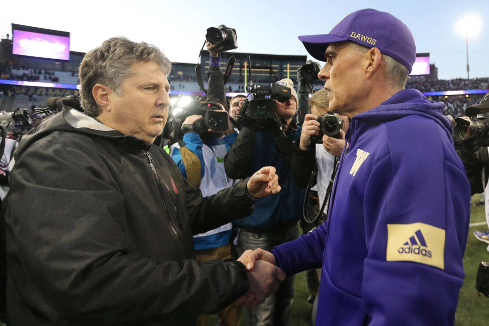 Head coach Mike Leach of the Washington State Cougars (left) and head coach Chris Petersen of the Washington Huskies shake hands after the Huskies defeated the Cougars 31-13 during their game at Husky Stadium on November 29, 2019 in Seattle, Washington. (Abbie Parr / Tribune News Service)