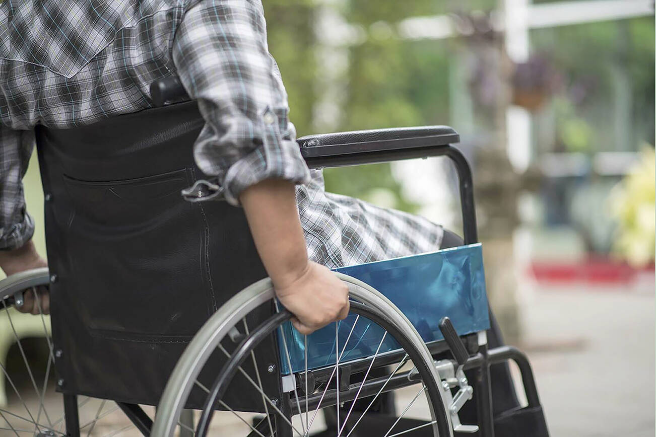 Close-up of senior woman hand on wheel of wheelchair during walk in hospital