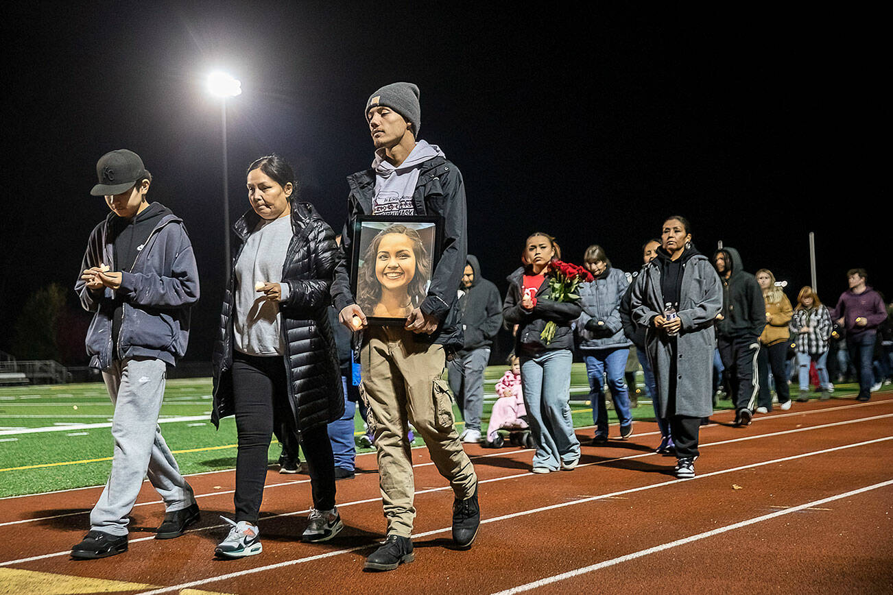 Kordelle Hammond holds a photograph of his cousin Shaylee Chuckulnaskit while her mother Lavina Phillips walks beside him during a memorial walk on the 10 year anniversary of the shooting at Marysville Pilchuck High School on Thursday, Oct. 24, 2024 in Marysville, Washington. (Olivia Vanni / The Herald)