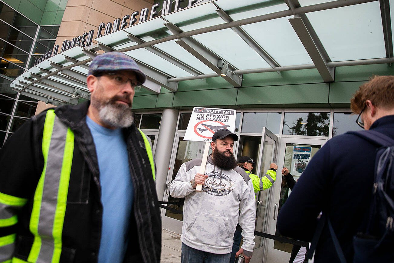 Matt Farnum, center, a machine repair mechanic at Boeing for 14 years, stands outside of Angel of the Winds Arena holding a “vote no” sign as people file inside to vote on the proposed contract on Wednesday, Oct. 23, 2024 in Everett, Washington. “I’ll be voting no until the collective approves the contract. It’s not just about me it’s about everyone else,” said Farnum. (Olivia Vanni / The Herald)