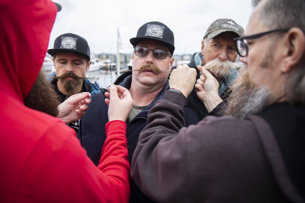 Tyler Nicholson, from Carbondale, Colorado, makes a face as he gets his mustache clipped together during a Guinness World Record Moustache Chain Attempt on Friday, Nov. 1, 2024 in Everett, Washington. (Olivia Vanni / The Herald)
