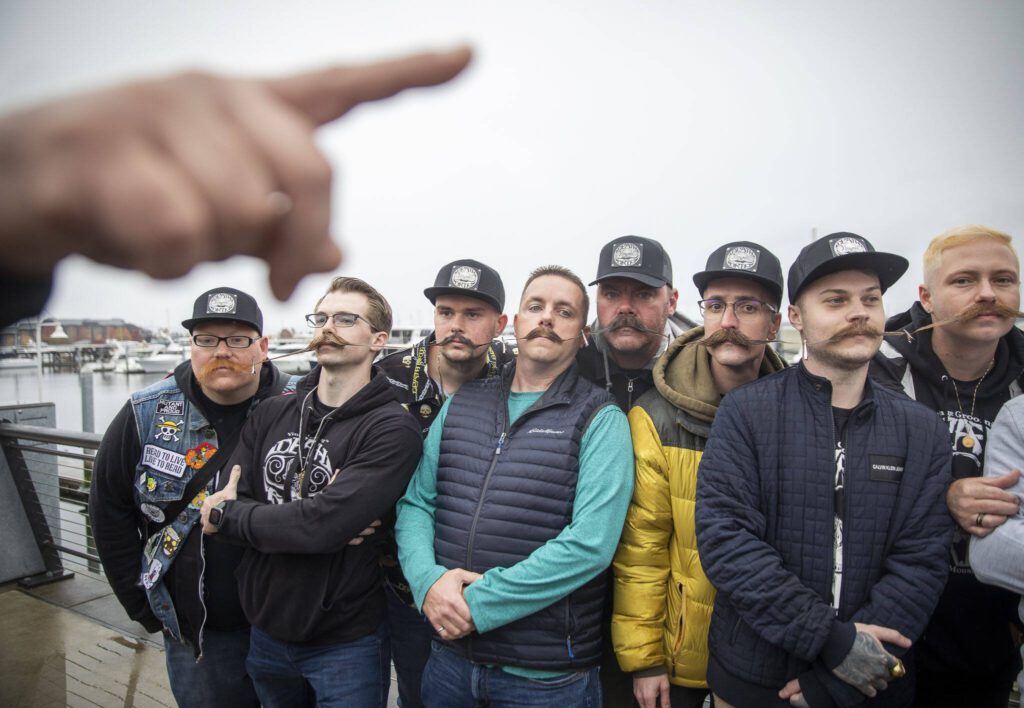 Dozens of people with mustaches clipped together wait to be measured for a Guinness World Record Mustache Chain Attempt on Friday, Nov. 1, 2024 in Everett, Washington. (Olivia Vanni / The Herald)
