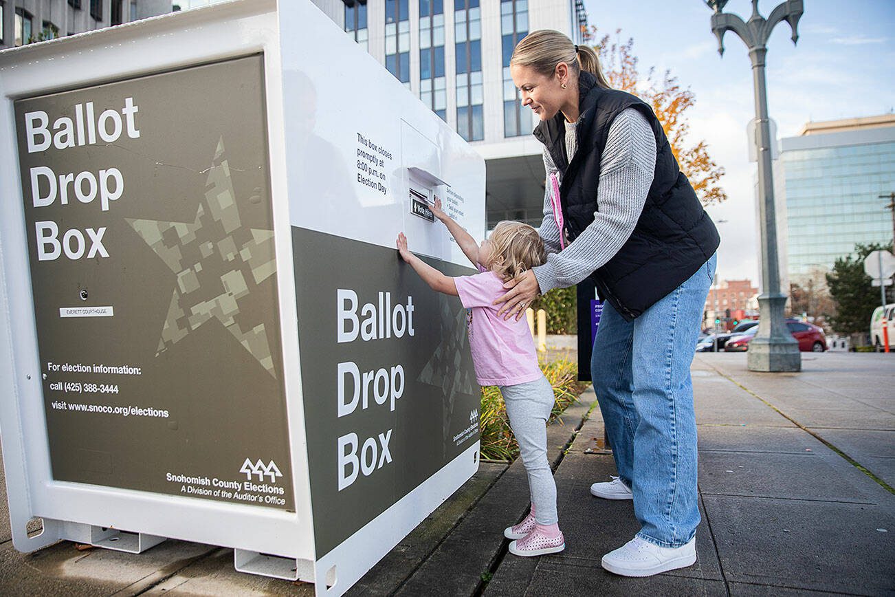 Carli Brockman lets her daughter Carli, 2, help push her ballot into the ballot drop box on the Snohomish County Campus on Tuesday, Nov. 5, 2024 in Everett, Washington. (Olivia Vanni / The Herald)