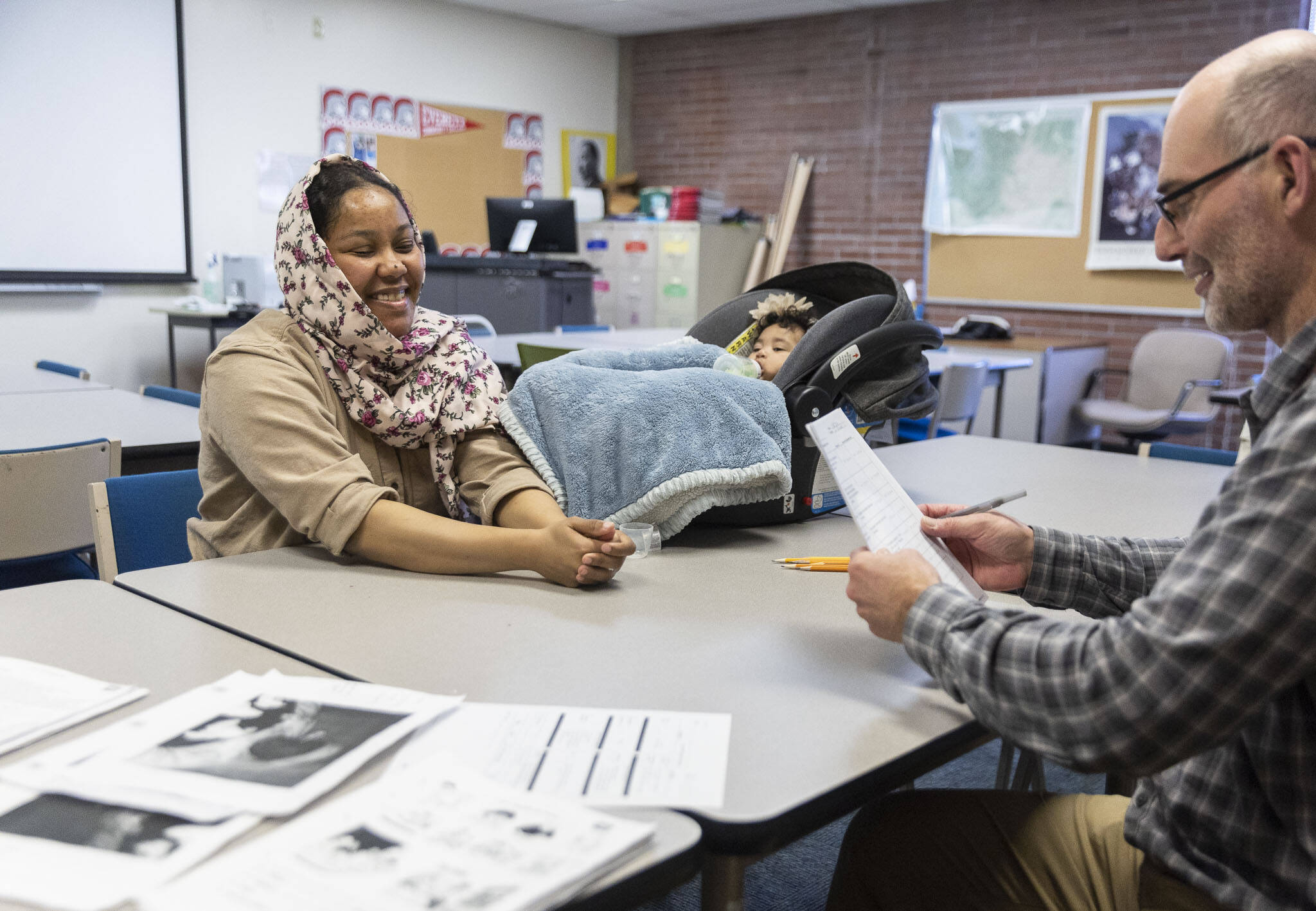 Refugee and Immigrant Services Northwest Senior Associate ESL Instructor James Wilcox, right, works on speaking and writing with Anfal Zaroug, 32, who is accompanied by her daughter Celia Hassen, 6 months, on Friday, Nov. 15, 2024 in Everett, Washington. (Olivia Vanni / The Herald)