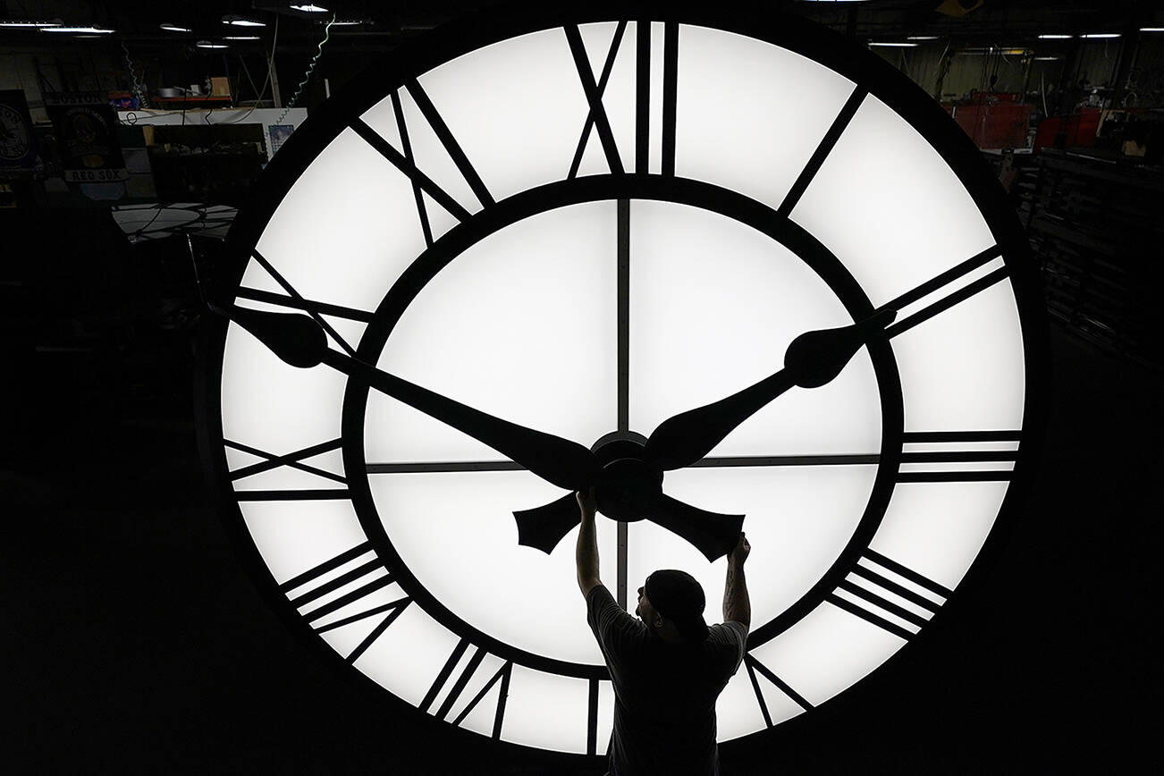 Electric Time technician Dan LaMoore adjusts a clock hand on a 1000-lb., 12-foot diameter clock constructed for a resort in Vietnam, Tuesday, March 9, 2021, in Medfield, Mass. Daylight saving time begins at 2 a.m. local time Sunday, March 14, 2021, when clocks are set ahead one hour. (AP Photo/Elise Amendola)